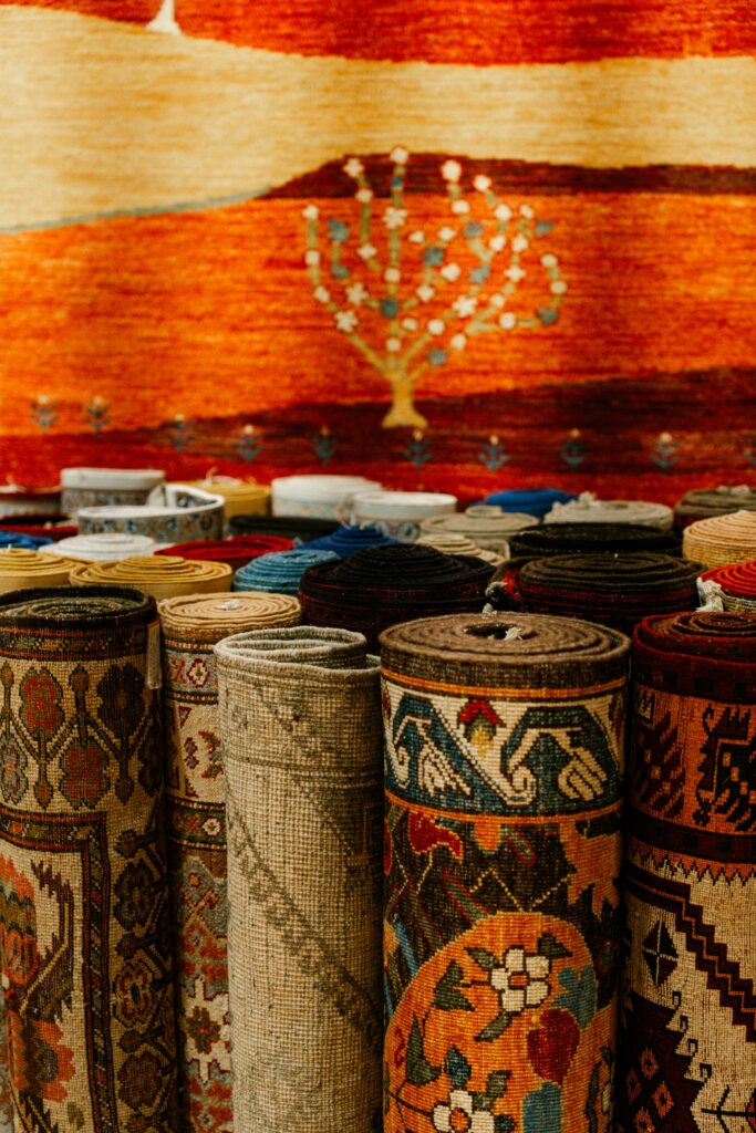 A vibrant display of rolled rugs with intricate patterns in a traditional market setting.